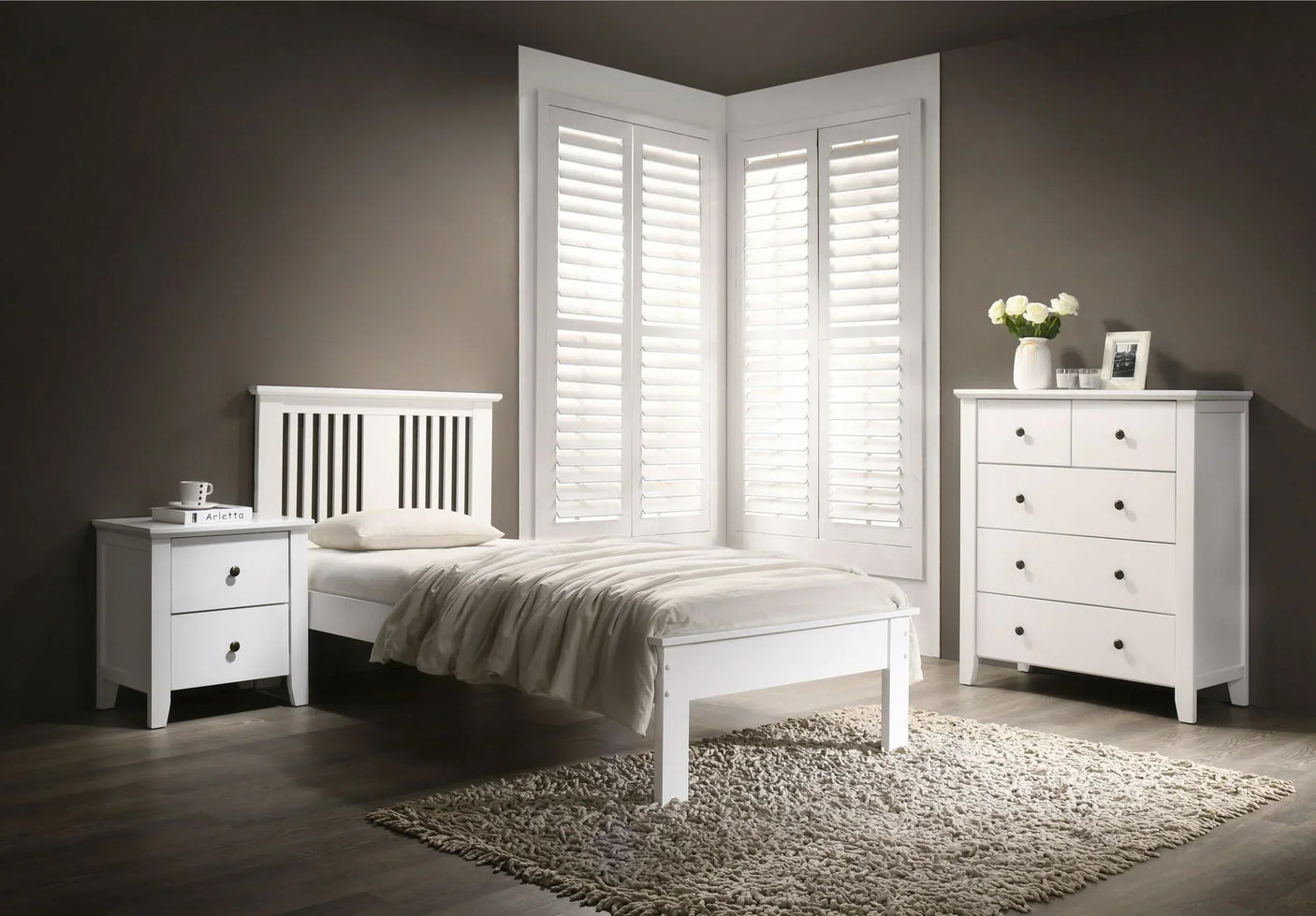 White bedroom furniture set with single bed, bedside table, chest of drawers, on wood floor