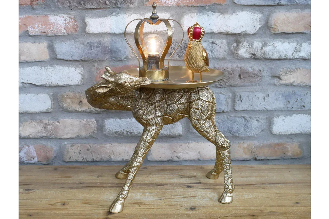 Gold giraffe side table with bulb lamp and crowned bird ornament on wood floor