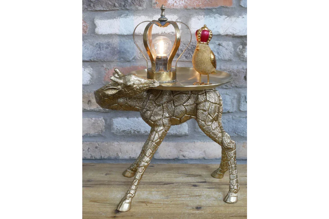Gold giraffe side table with a bird ornament and decorative lamp on wooden floor