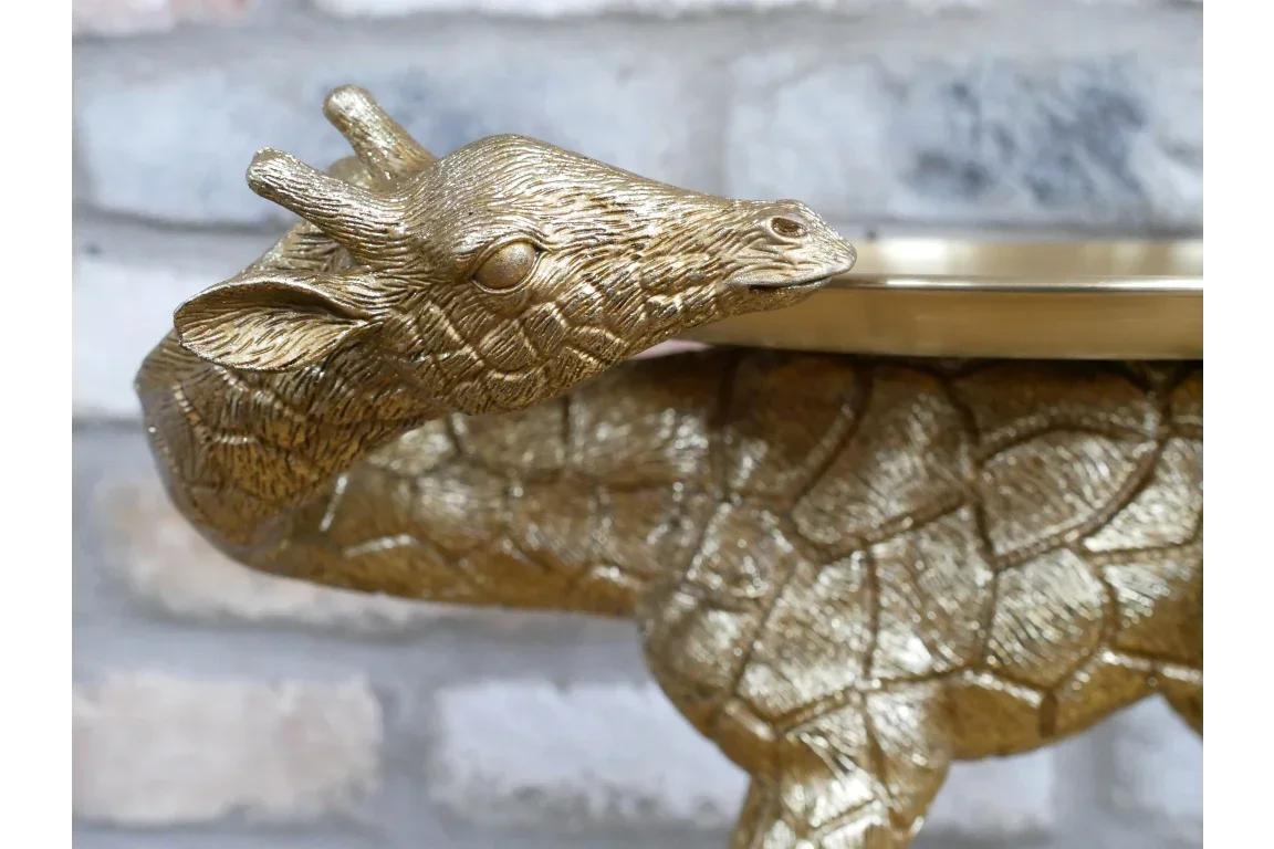 Gold giraffe shaped side table with textured finish against brick wall