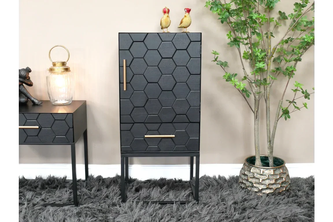 Black hexagonal pattern cabinet with gold handles beside a faux plant on grey rug