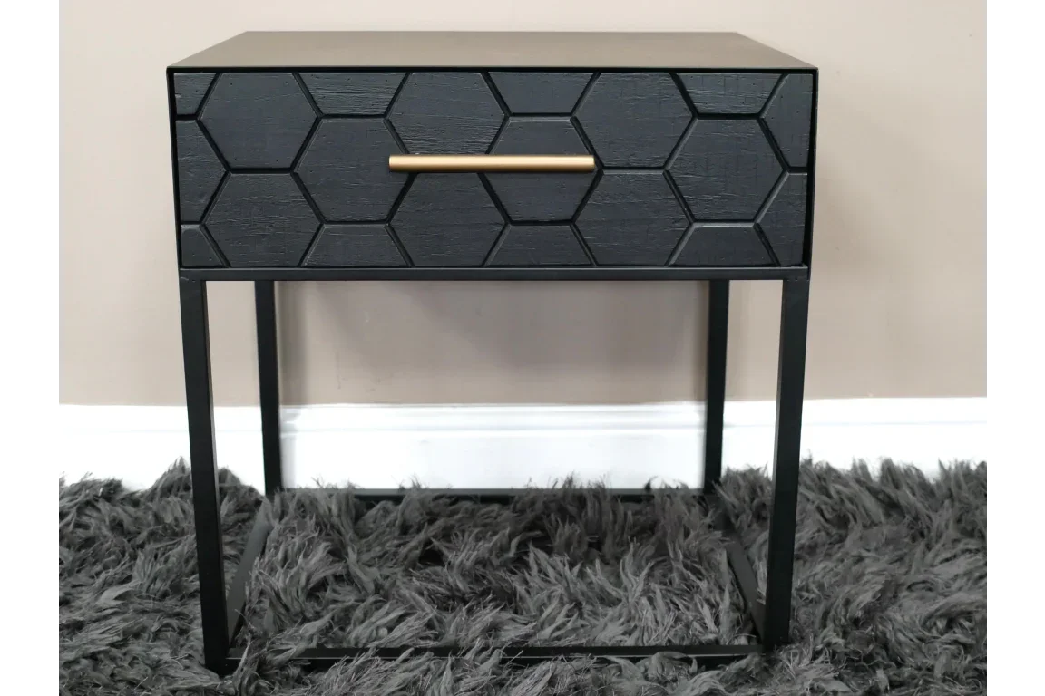 Black bedside table with honeycomb pattern drawer and gold handle on metal legs