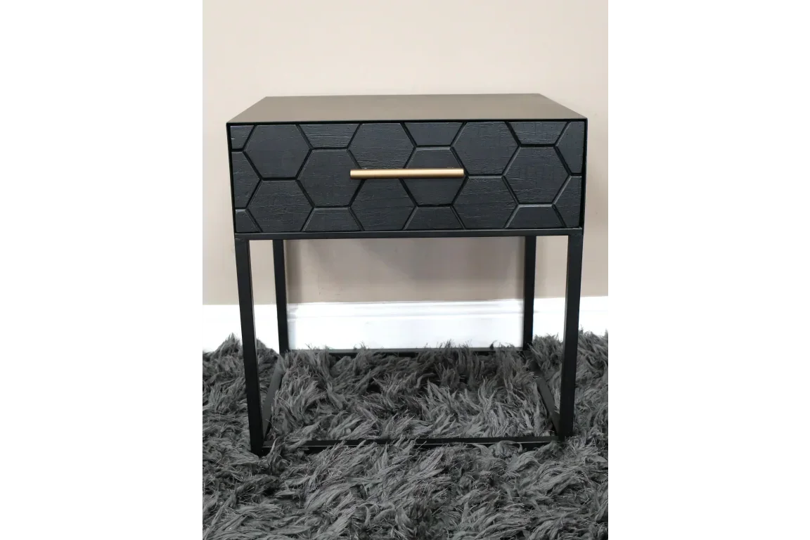 Black bedside table with geometric drawer front and gold handle on black metal legs