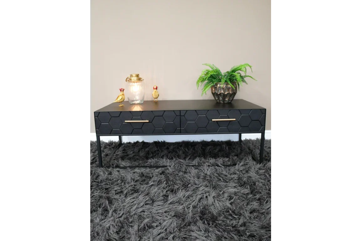 Black coffee table with hexagon drawer fronts and gold handles on grey shag rug