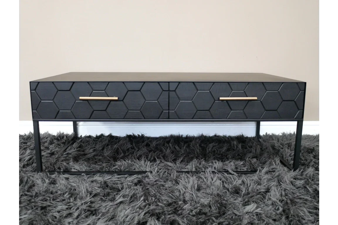 Black coffee table with hexagon pattern drawers and gold handles on a shaggy rug