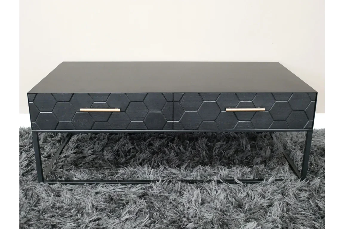 Black coffee table with hexagonal drawer fronts and gold handles on grey shag rug