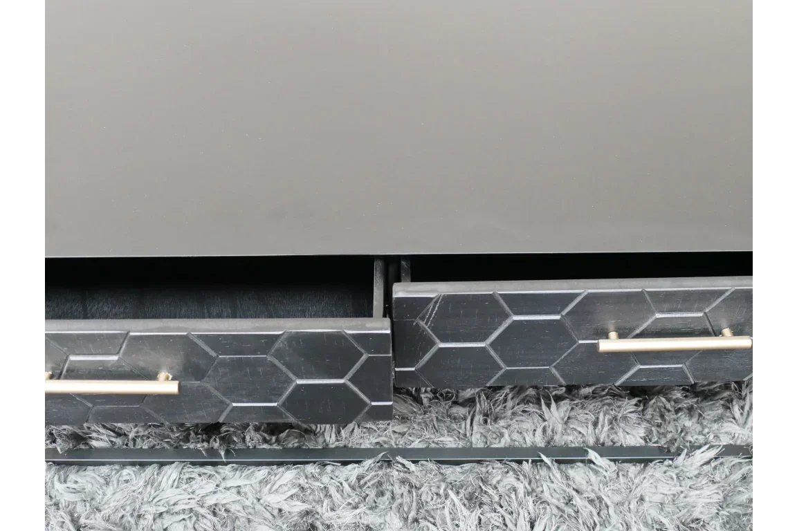 Black geometric drawer front on wooden cabinet with gold handles, close-up view