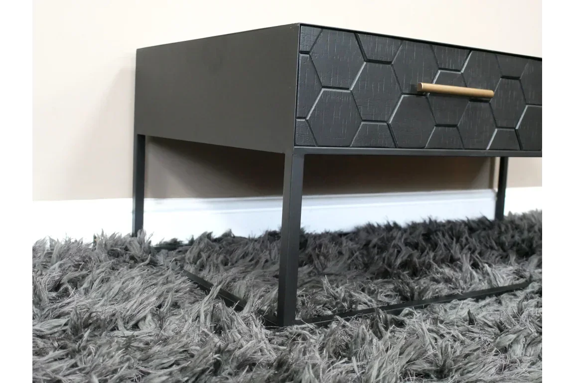 Black bedside table with metal legs and honeycomb drawer front on grey shaggy rug