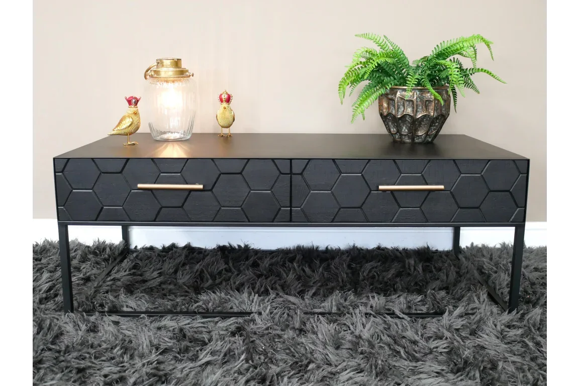 Black hexagon pattern coffee table with brass handles, lamp, gold ornaments and potted fern