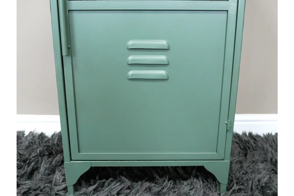 Green metal cabinet door with three horizontal vents on textured rug