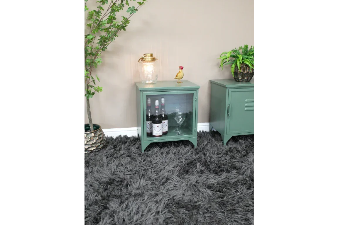 Green metal bedside cabinet with glass door, wine bottles, and glasses on grey shag rug