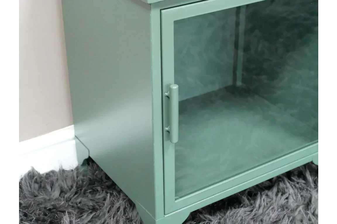 Green metal cabinet with glass door and handle on grey textured rug