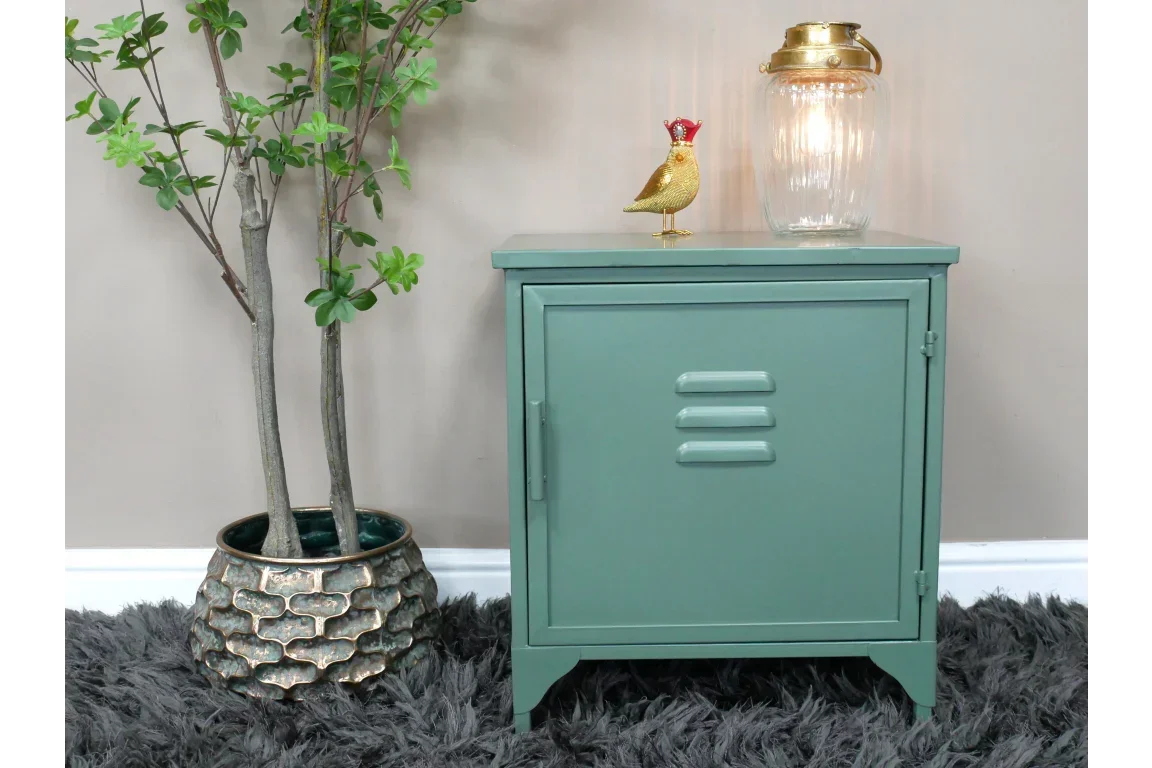 Green metal bedside cabinet with single door, styled with lamp and gold bird ornament