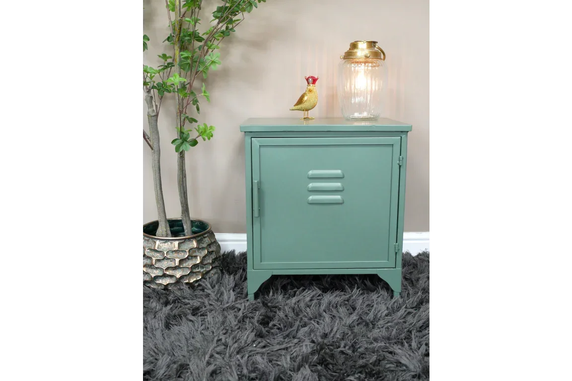 Green metal bedside cabinet with single door, lamp and ornament on top, on grey rug