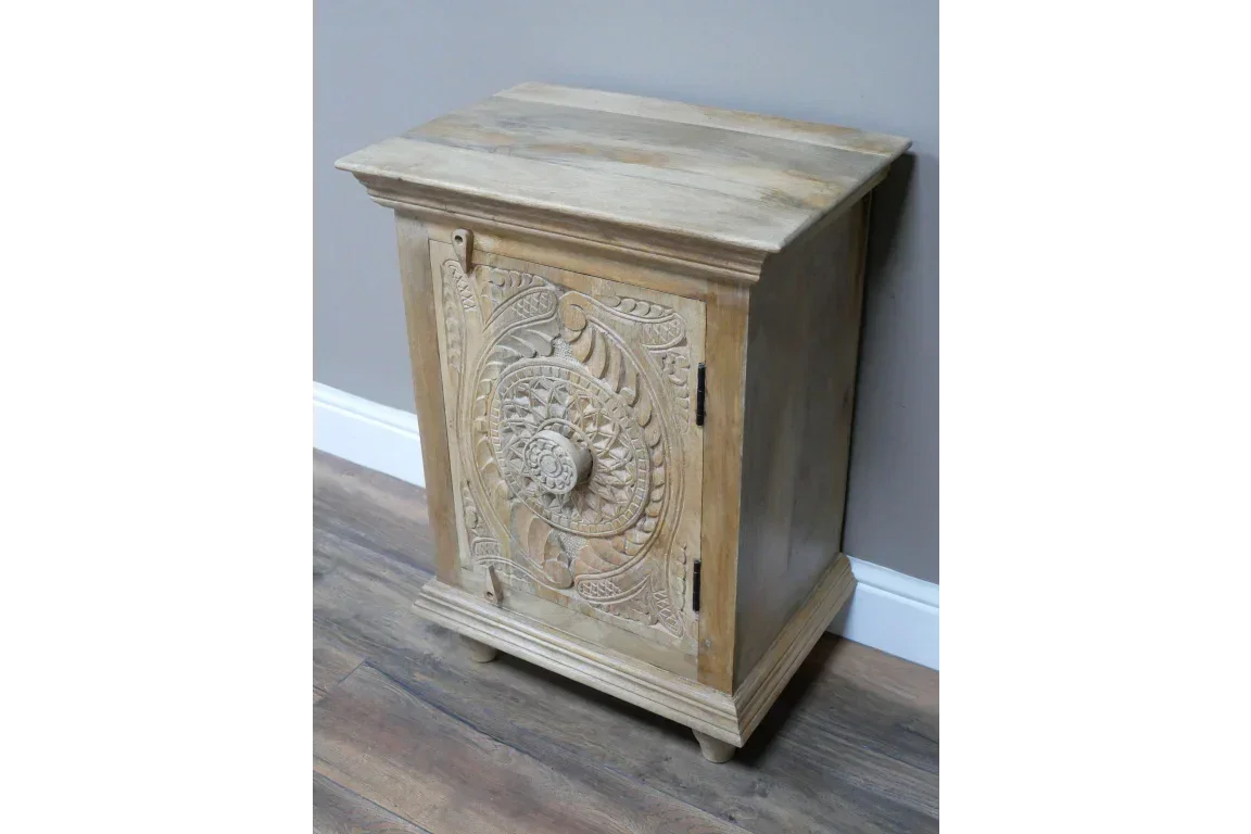 Wooden cabinet with ornate carved door and knob, natural finish, placed on hardwood floor