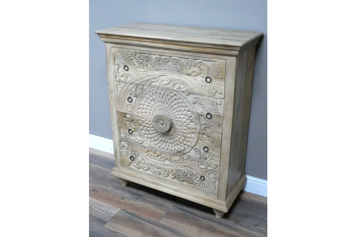 Light wood chest of drawers with carved floral and circular detailing, on wood floor