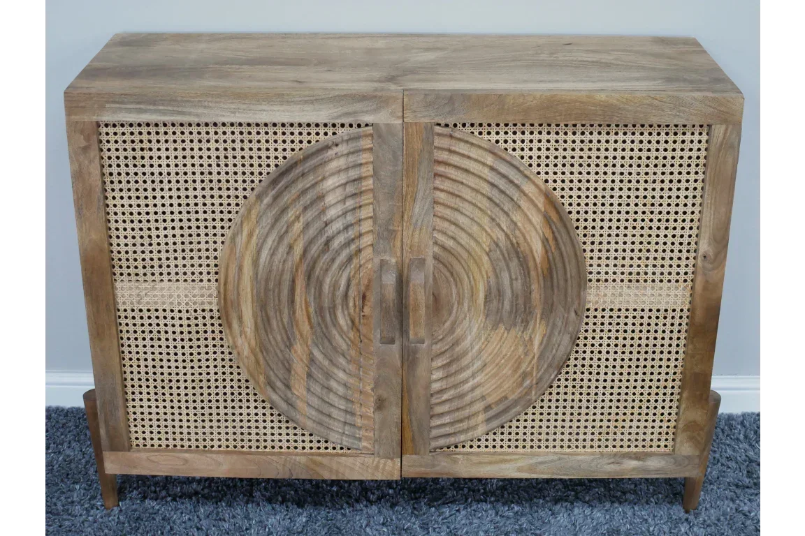 Wooden sideboard with rattan doors and circular carved pattern on front, on blue carpet