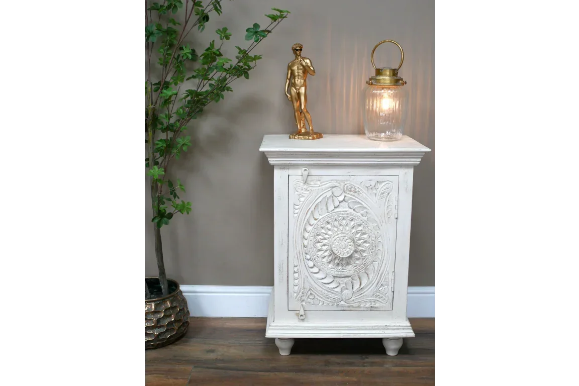 White carved wood cabinet with floral pattern door in living room, decor on top