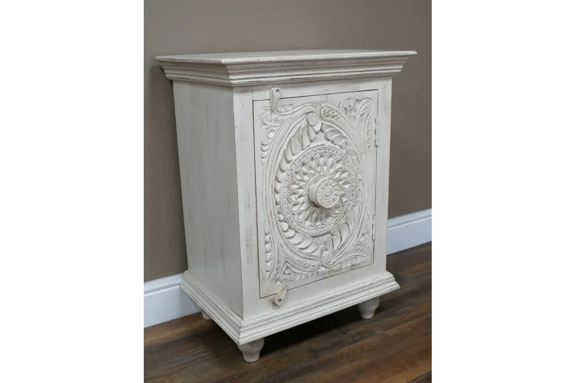 White carved wooden cabinet with ornate floral door panel on wood floor