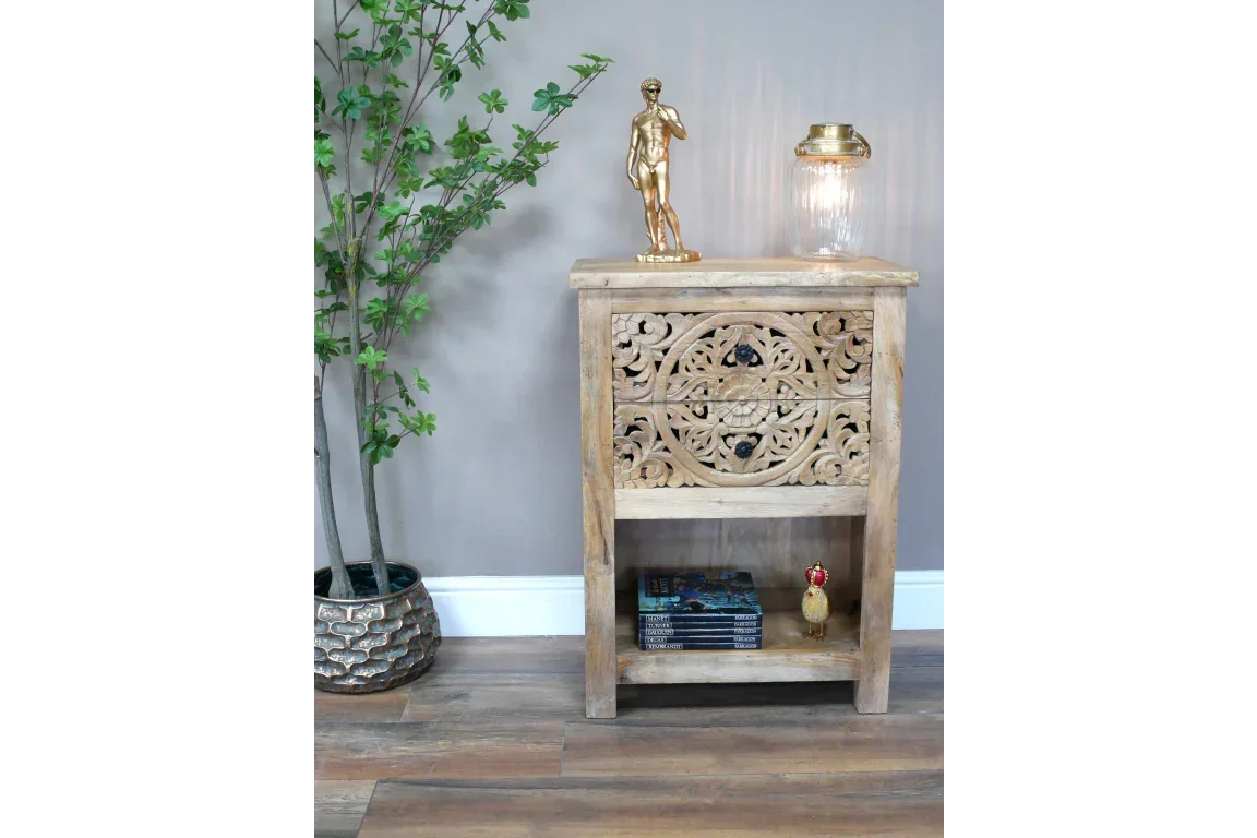 Carved wooden side cabinet with ornate front panel and open shelf, styled in modern living space