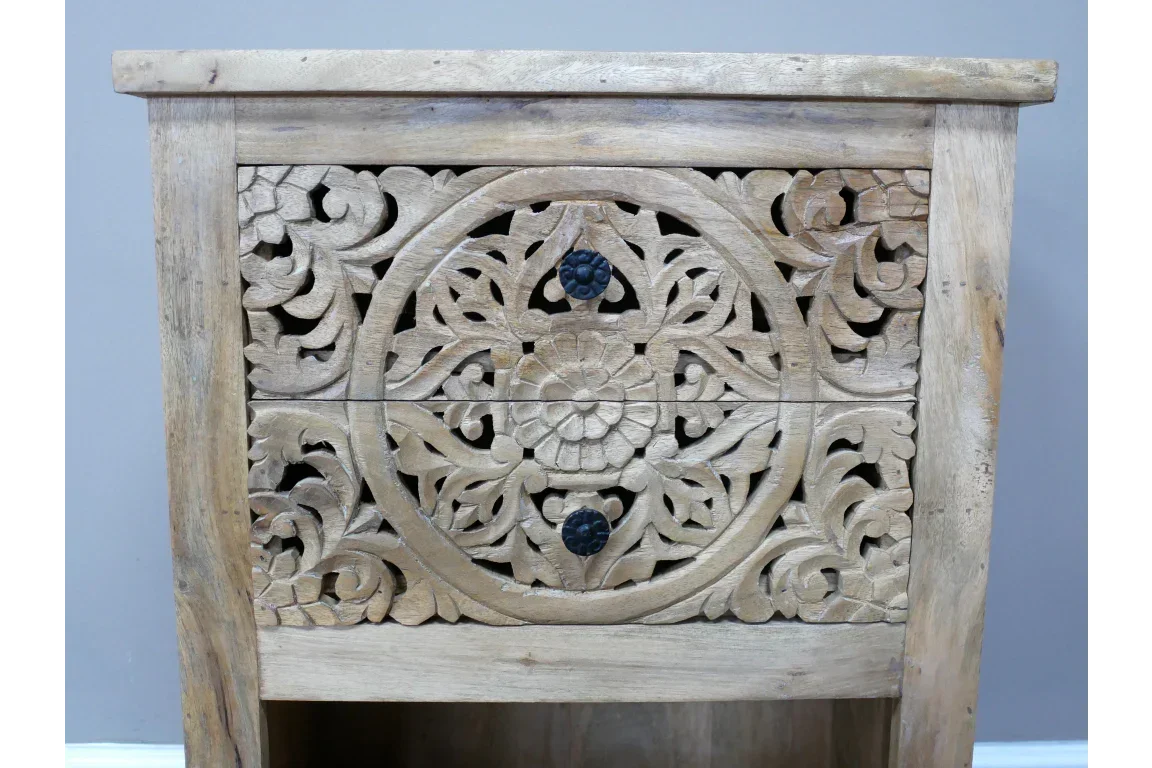 Carved wood bedside table with floral pattern and black drawer knobs, natural finish