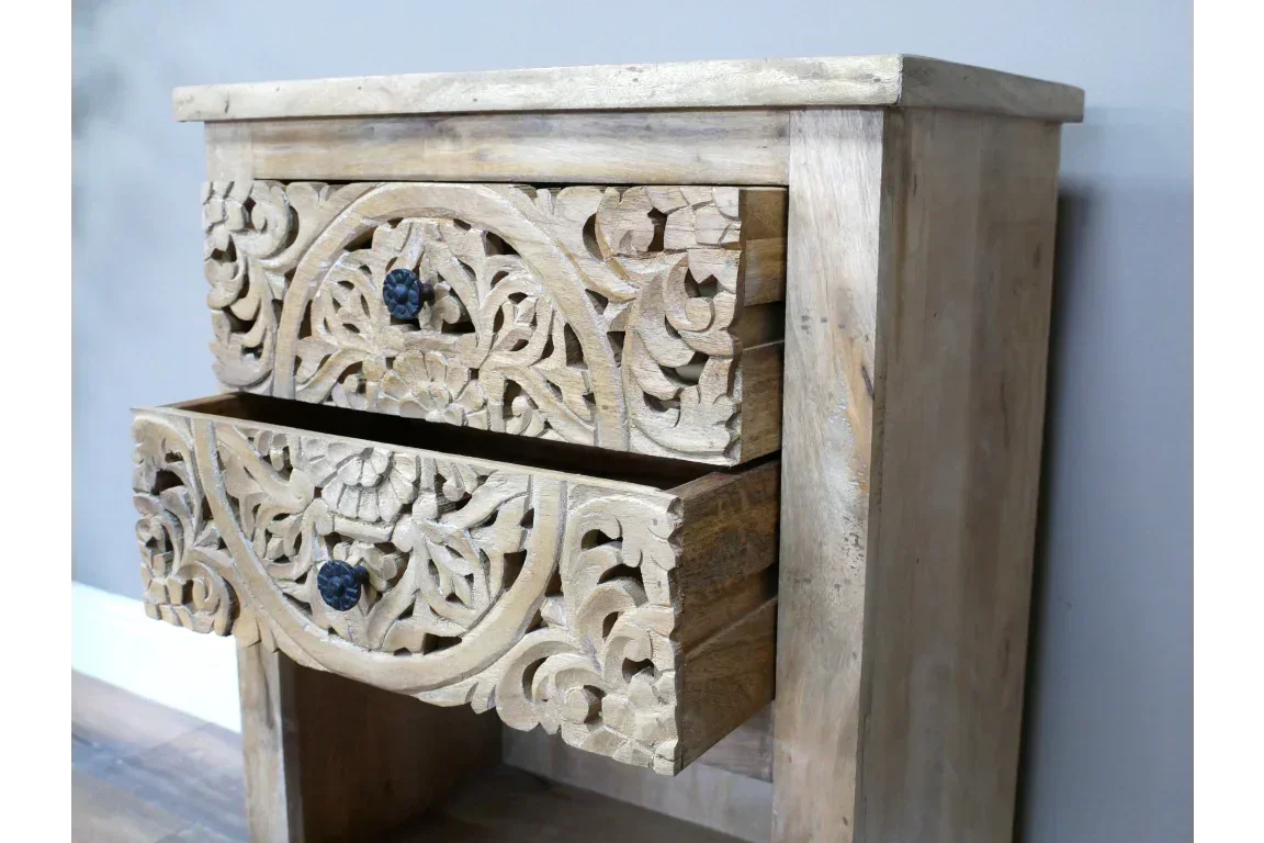 Mango wood bedside table with two carved drawers and black knobs, side angle view
