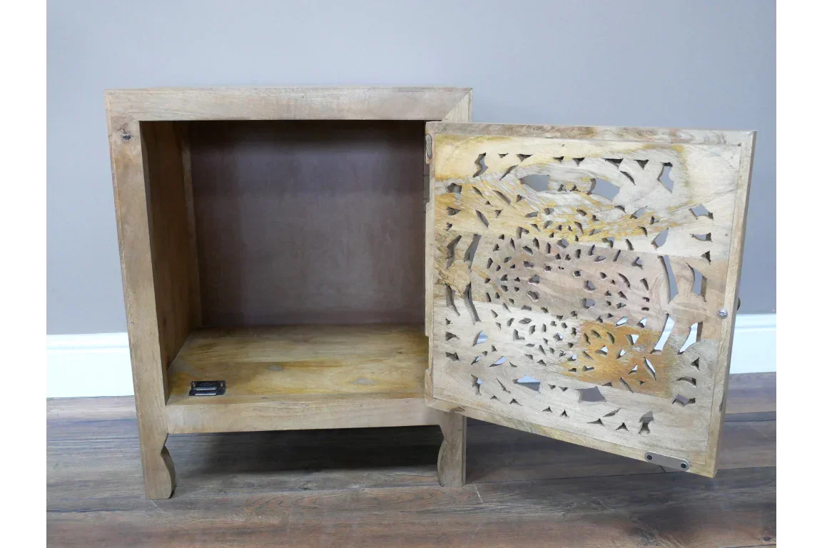 Wooden bedside cabinet with open carved door and natural finish on wooden floor