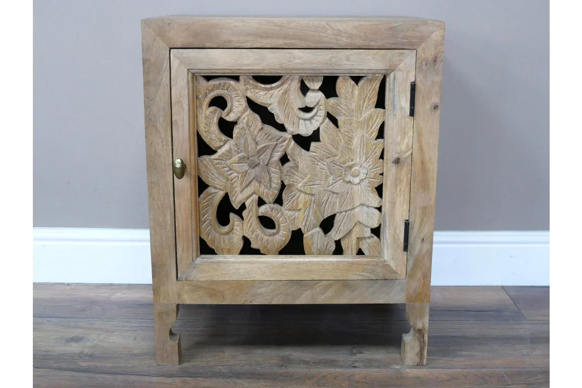 Carved wooden cabinet with floral pattern door and brass knob on laminate floor