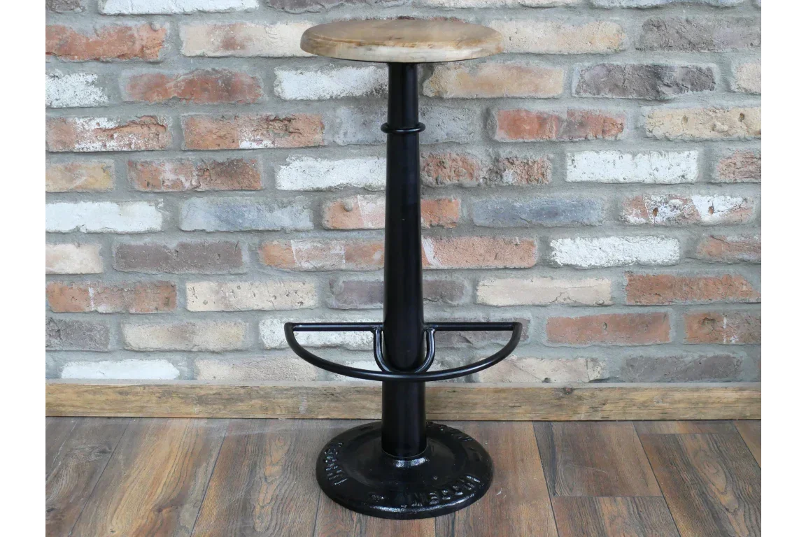 Industrial bar stool with round wooden seat and black metal base on wood floor