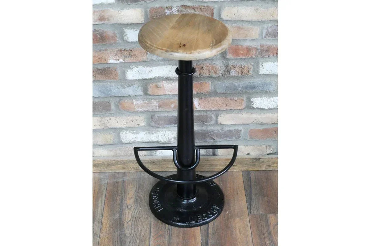 Industrial bar stool with round wooden seat and black metal base on wood floor