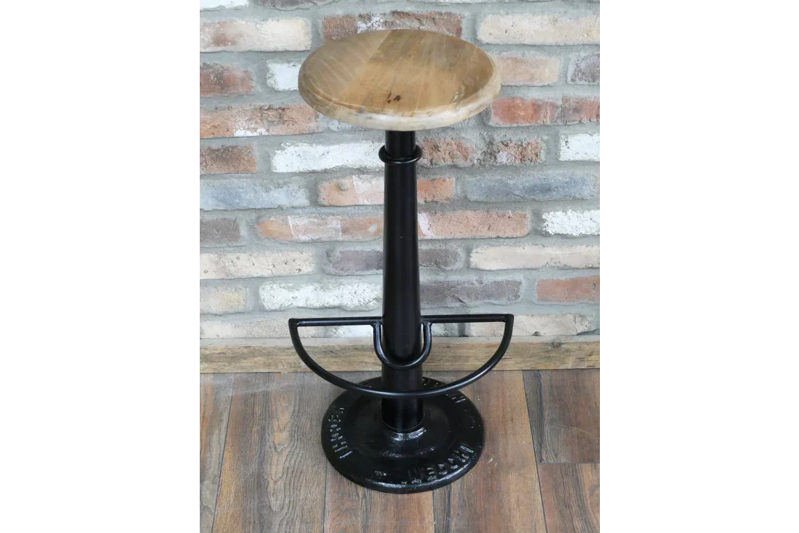Industrial bar stool with round wooden seat and black metal base on wood floor