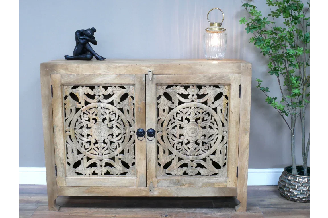 Carved wood cabinet with ornate floral doors and black metal knobs in living room setting
