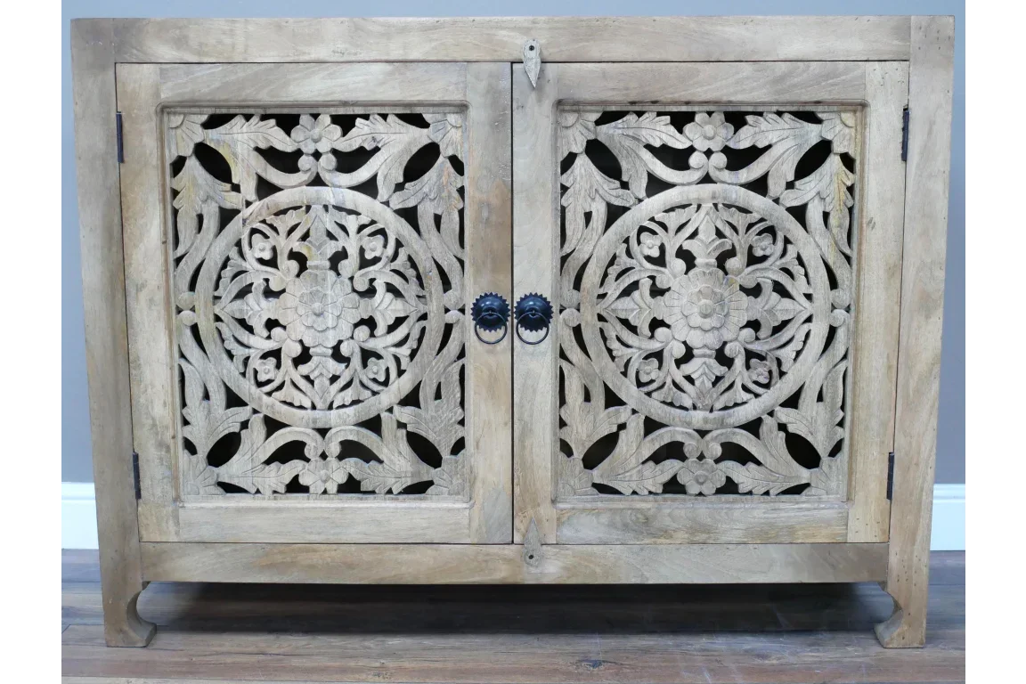 Carved wood sideboard with floral mandala doors and round metal handles on wooden floor