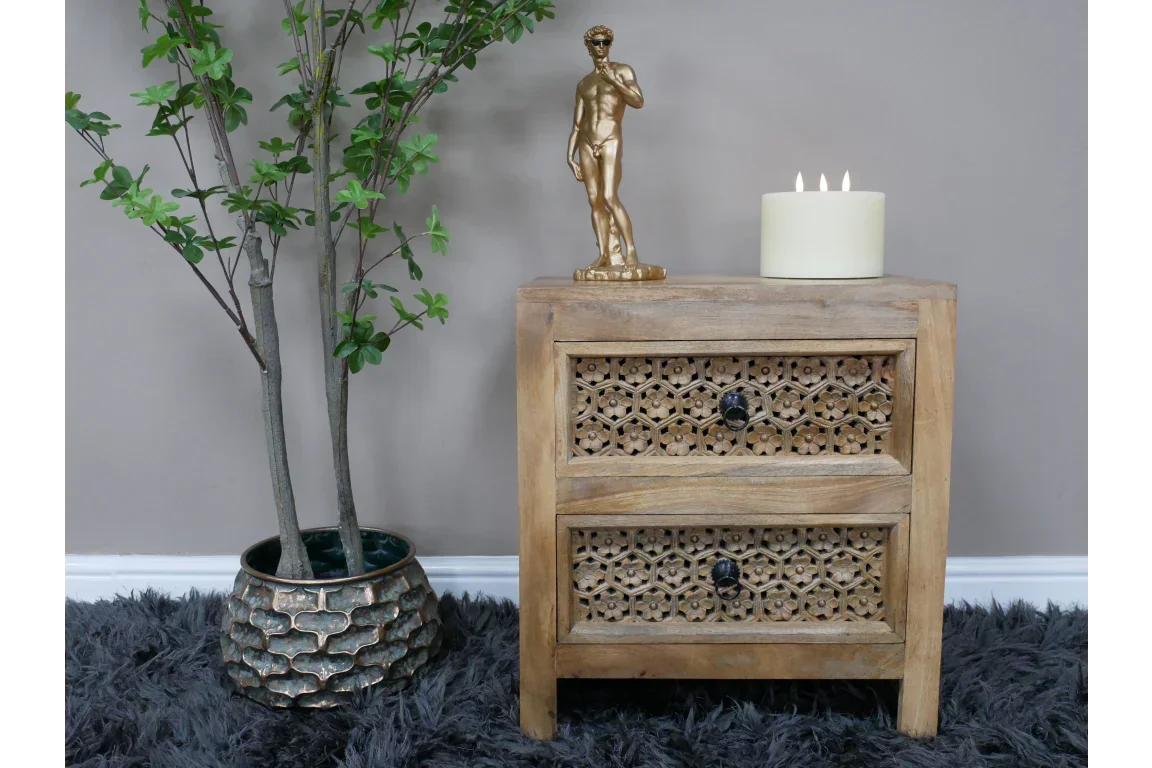 Carved wooden bedside table with two drawers, black knobs, inlaid detail, styled with decor