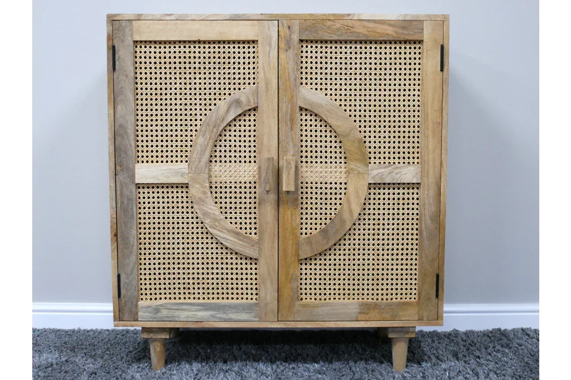 Natural wood cabinet with rattan doors and circle detail on front, shown on grey carpet