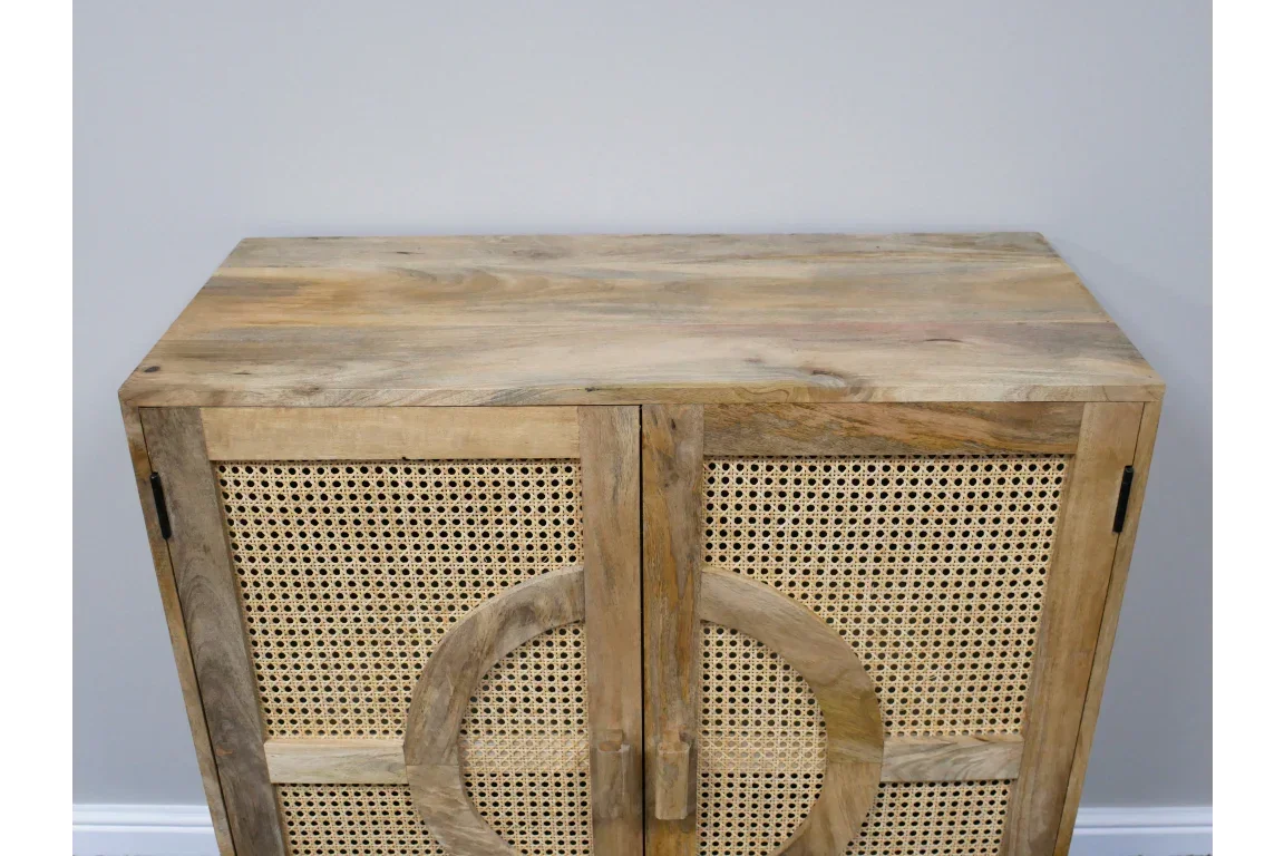 Wooden sideboard with rattan panel doors and circular detail against a grey wall