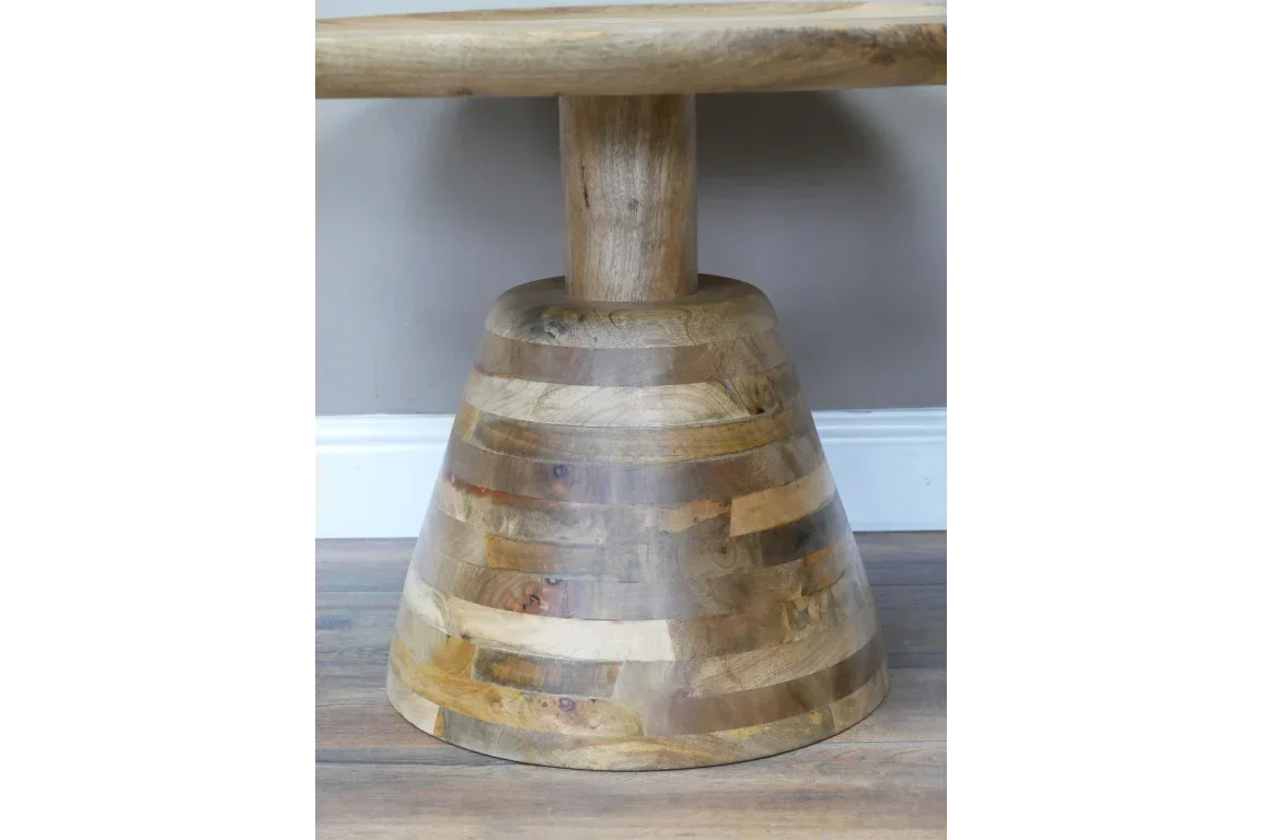 Round wooden dining table with a chunky, striped pedestal base on wooden floor