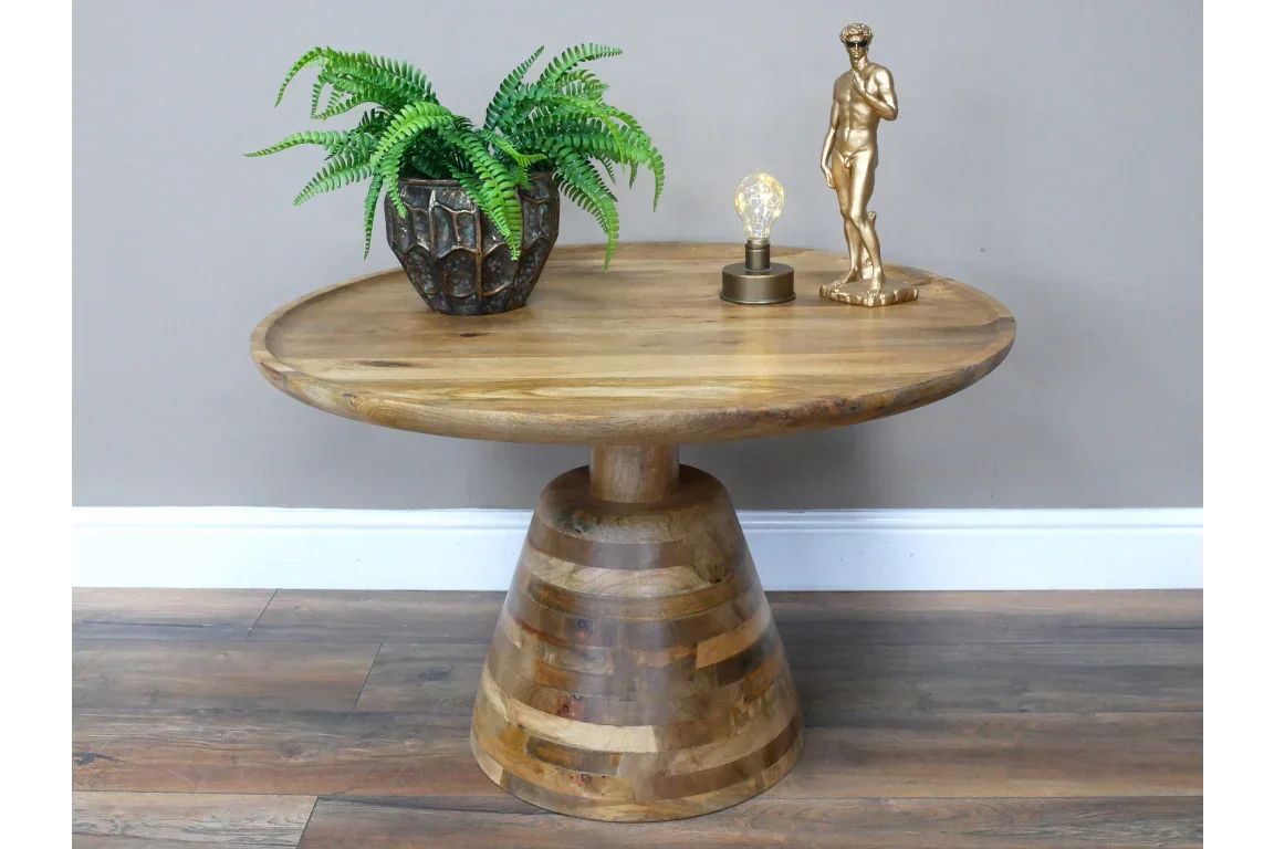 Round wooden coffee table with plant pot, small lamp, and gold figurine on top