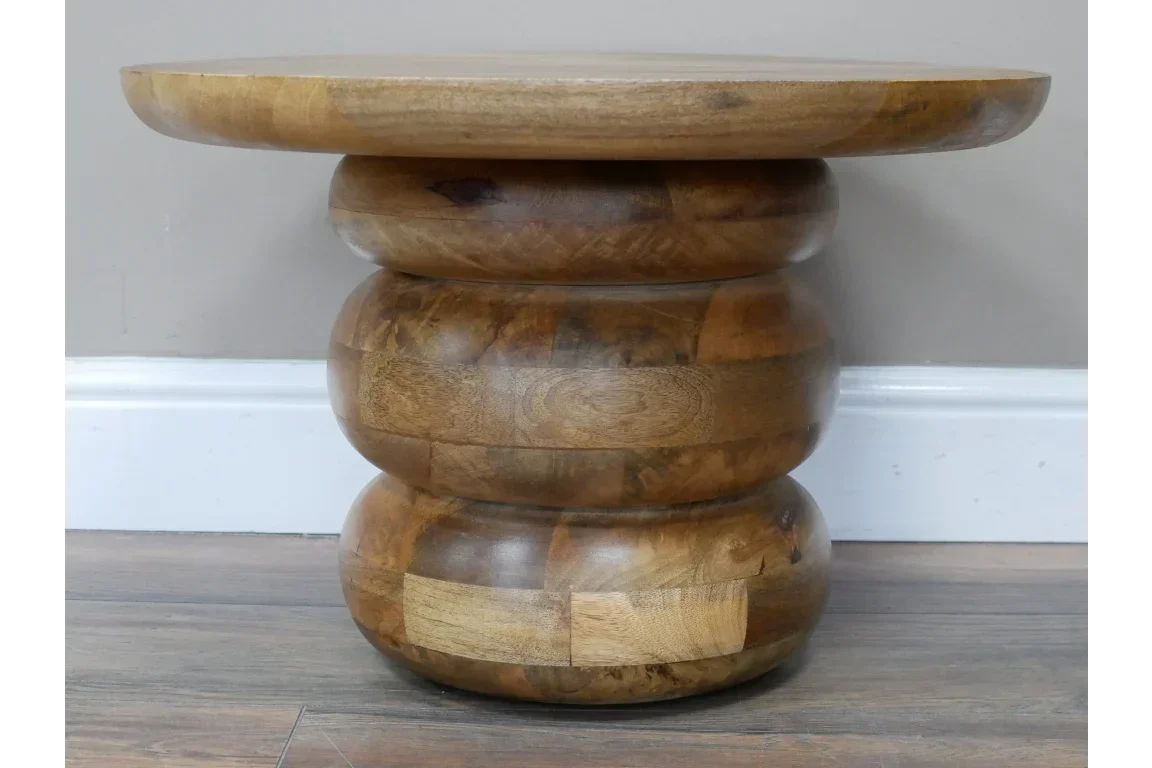 Chunky round wooden side table with natural wood grain on flat base, shown against wall
