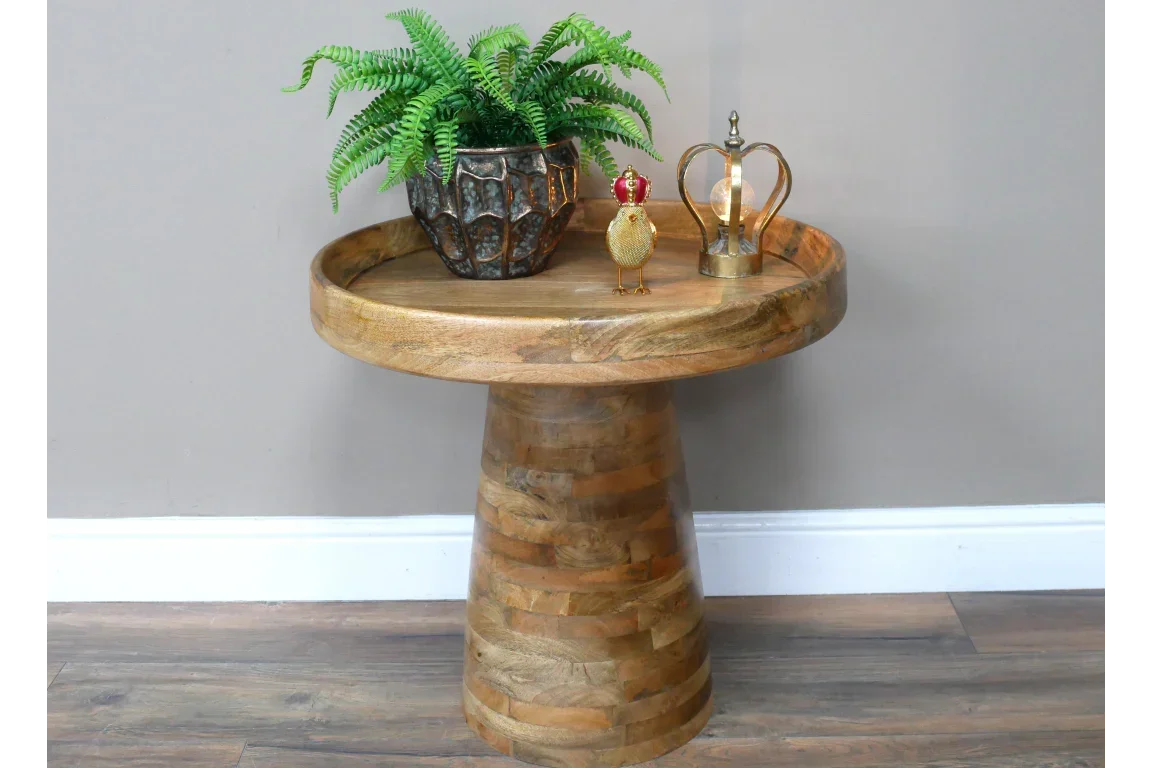 Round wooden side table with plant pot and decorative ornaments on wood floor