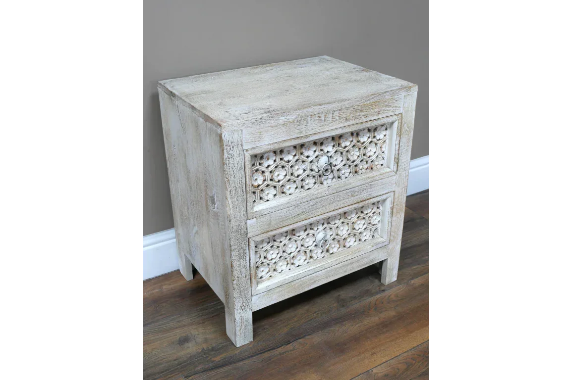 Whitewashed wooden chest of drawers with carved floral detail and rustic finish