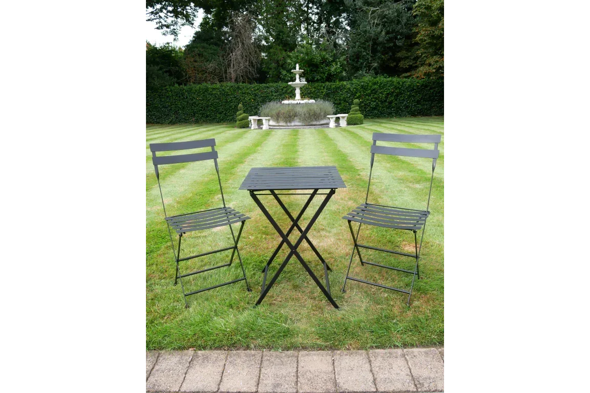 Black metal bistro set with two chairs and square table on garden lawn