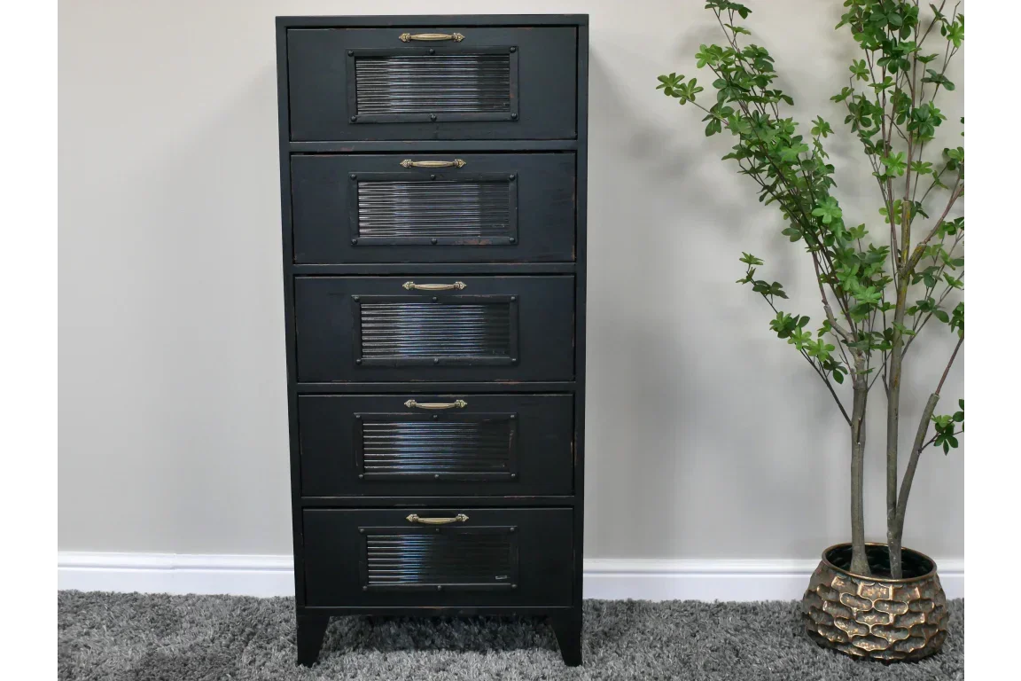 Tall black metal chest of drawers with five ribbed front panels, placed on grey carpet