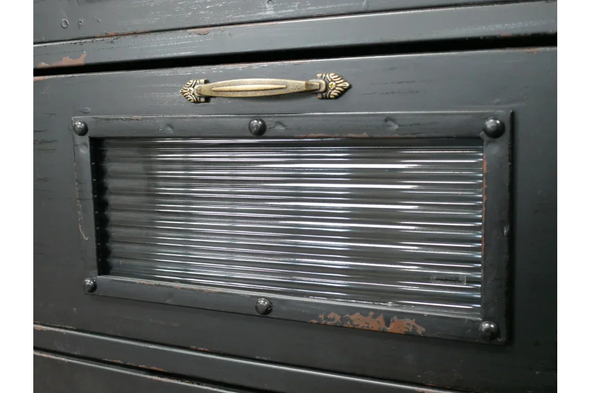 Close-up of black wooden storage cabinet with ribbed glass panel and brass handle