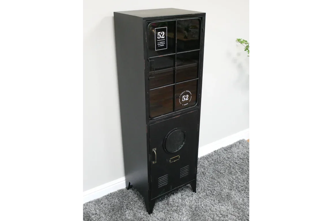 Black metal storage cabinet with glass door and industrial accents on grey carpet