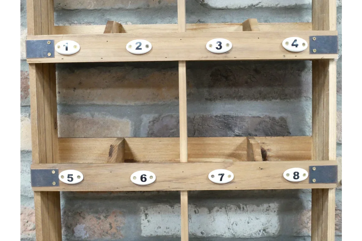 Wooden pigeon hole storage unit with numbered slots against brick wall