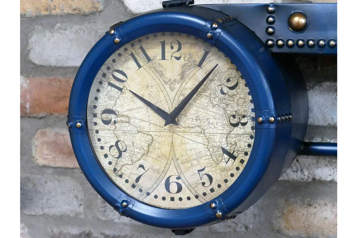 Blue metal wall clock with vintage world map face against exposed brick wall