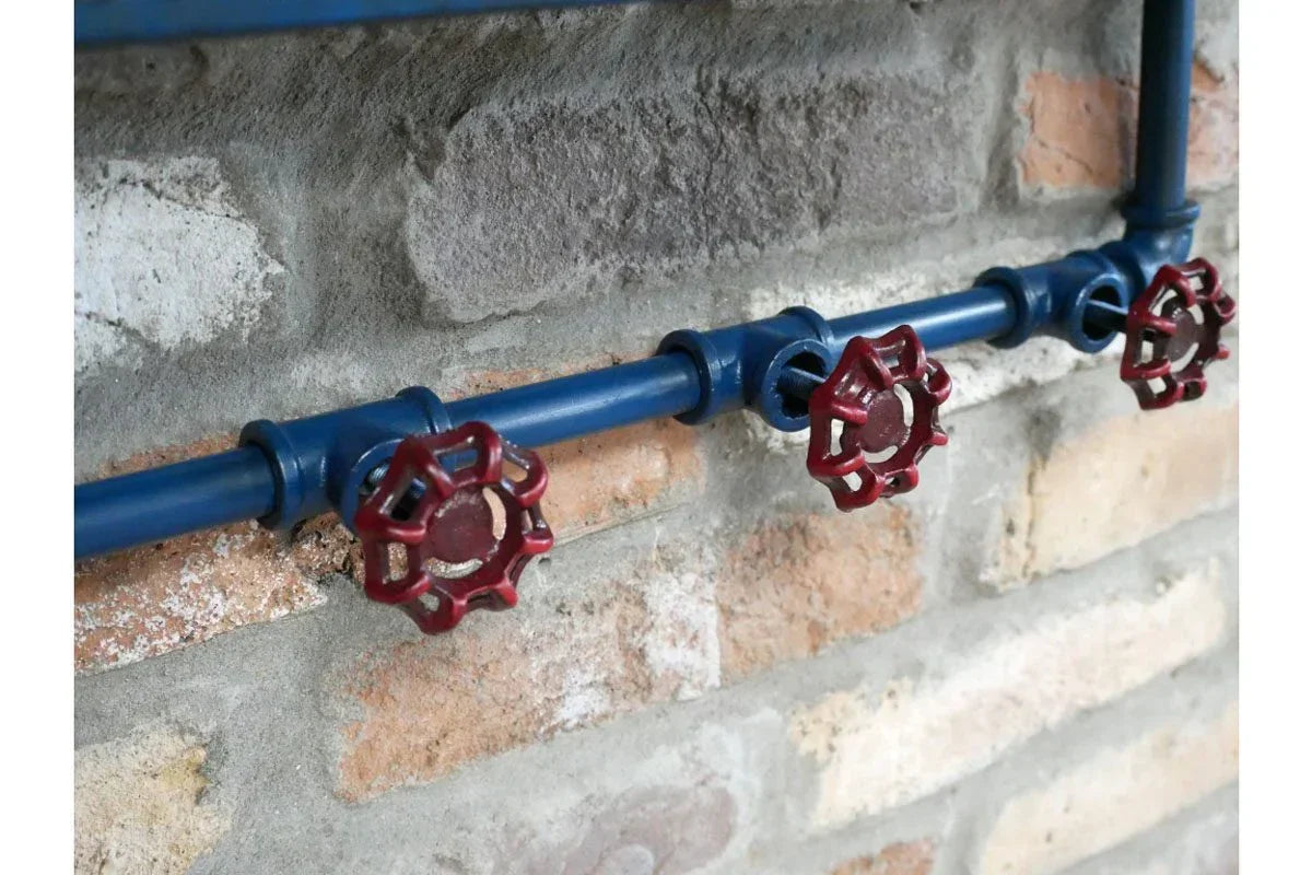 Industrial style coat rack with blue metal pipe and red valve hooks on brick wall