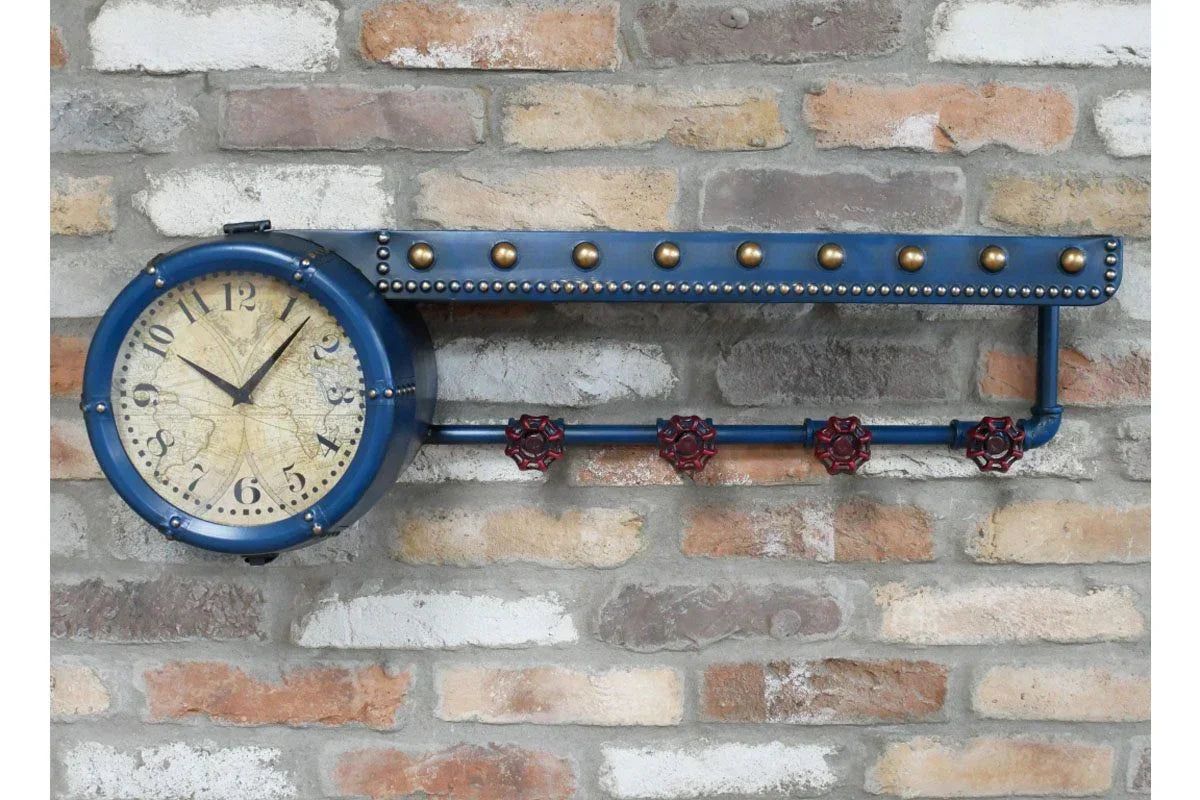 Industrial wall clock with blue metal frame, brass accents, and red valve detail on brick wall