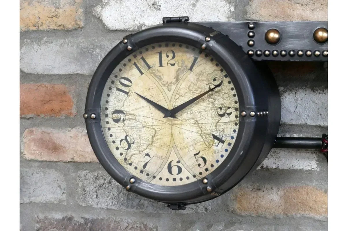 Industrial wall clock with vintage world map dial and metal frame on exposed brick wall